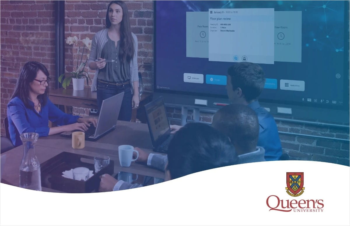 Business team reviewing floor plans on a SMART interactive display in a modern brick-walled office.