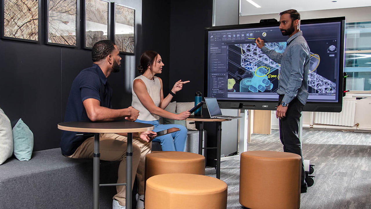 A team of three professionals collaborating around a SMART interactive display showing architectural design plans.