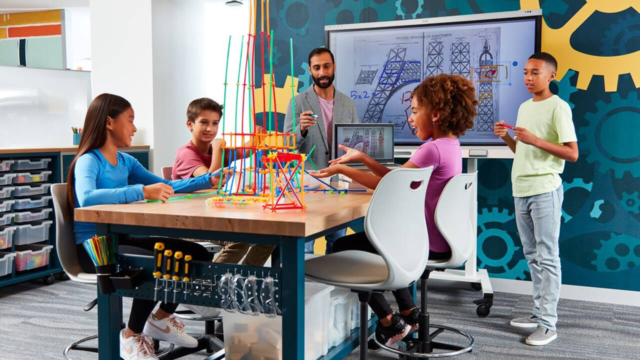 Students engaging in a creative STEM project with a SMART board in the background, showcasing interactive learning.